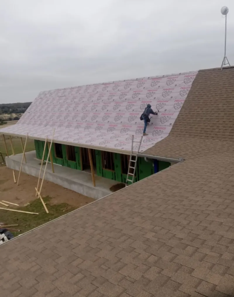 Worker preparing underlayment for a metal roof installation in Kochville